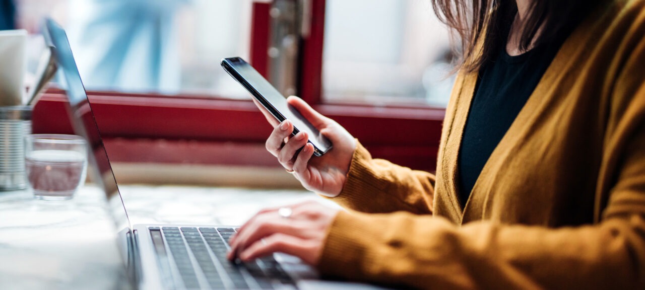 Woman at Restaurant Table with Phone and Laptop